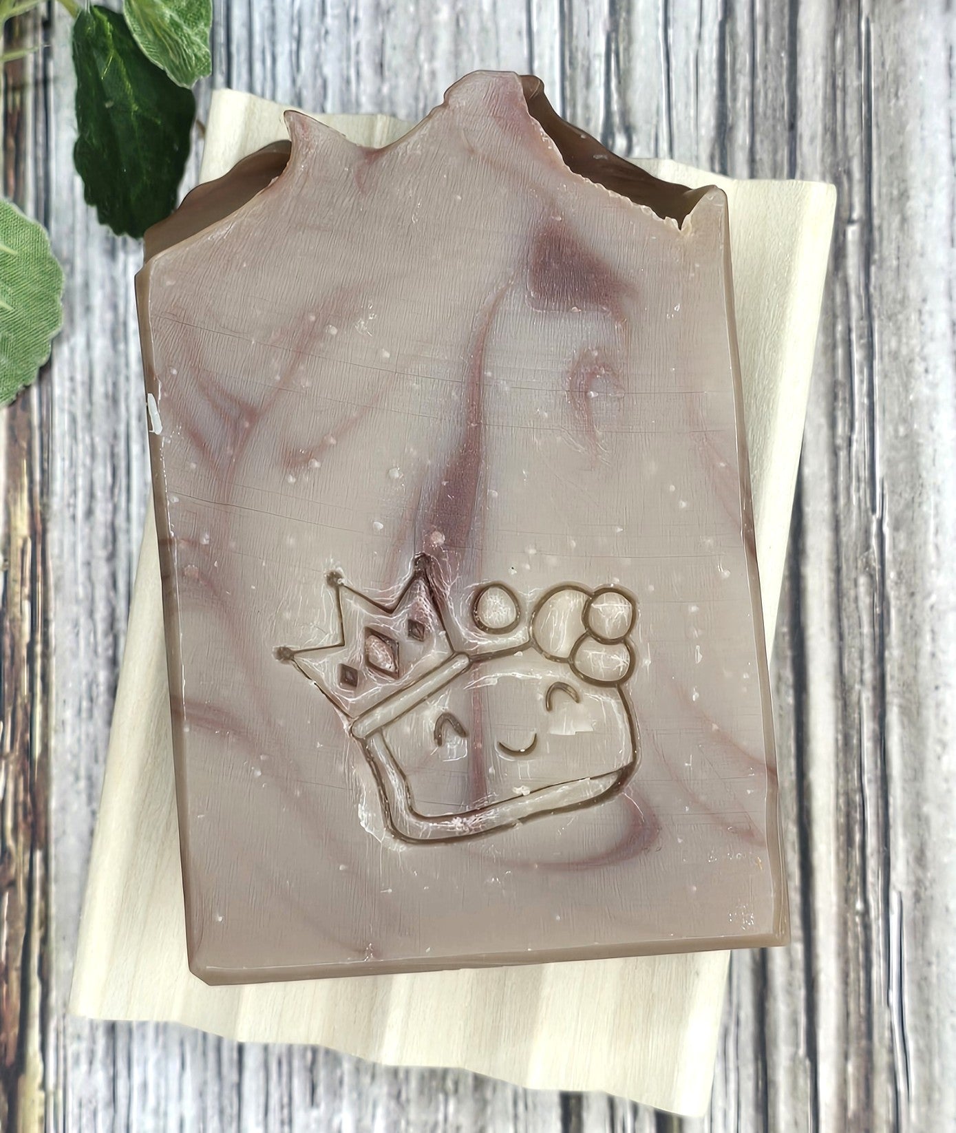 Bar of soap with a crown design on a wooden surface