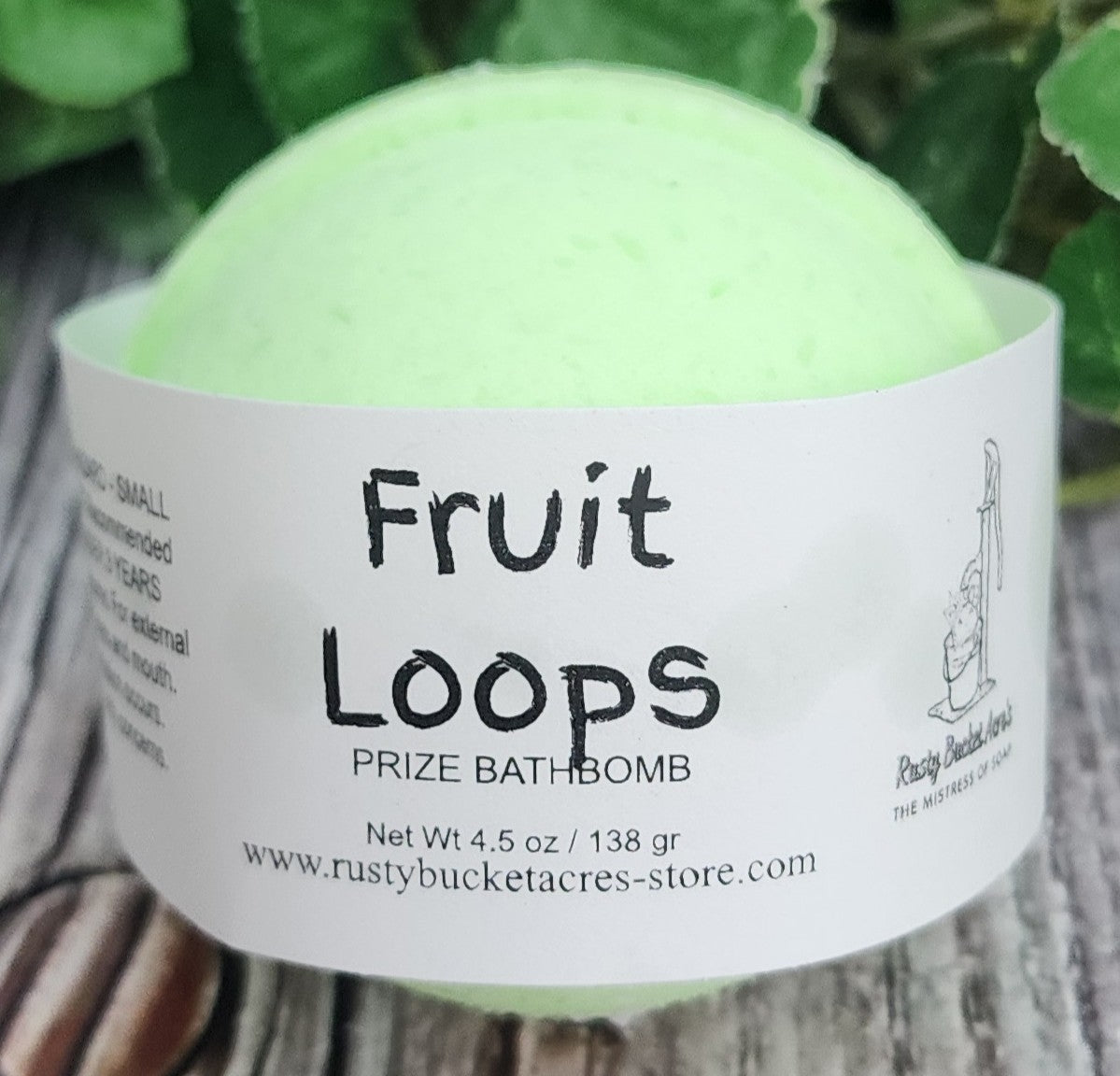 Green bath bomb with a label on a wooden surface and leafy background