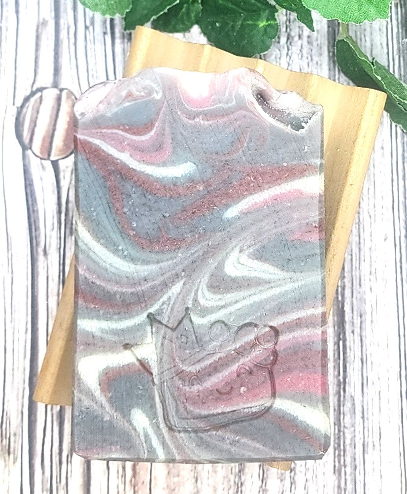 Marbled soap bar with a wooden holder on a wooden surface
