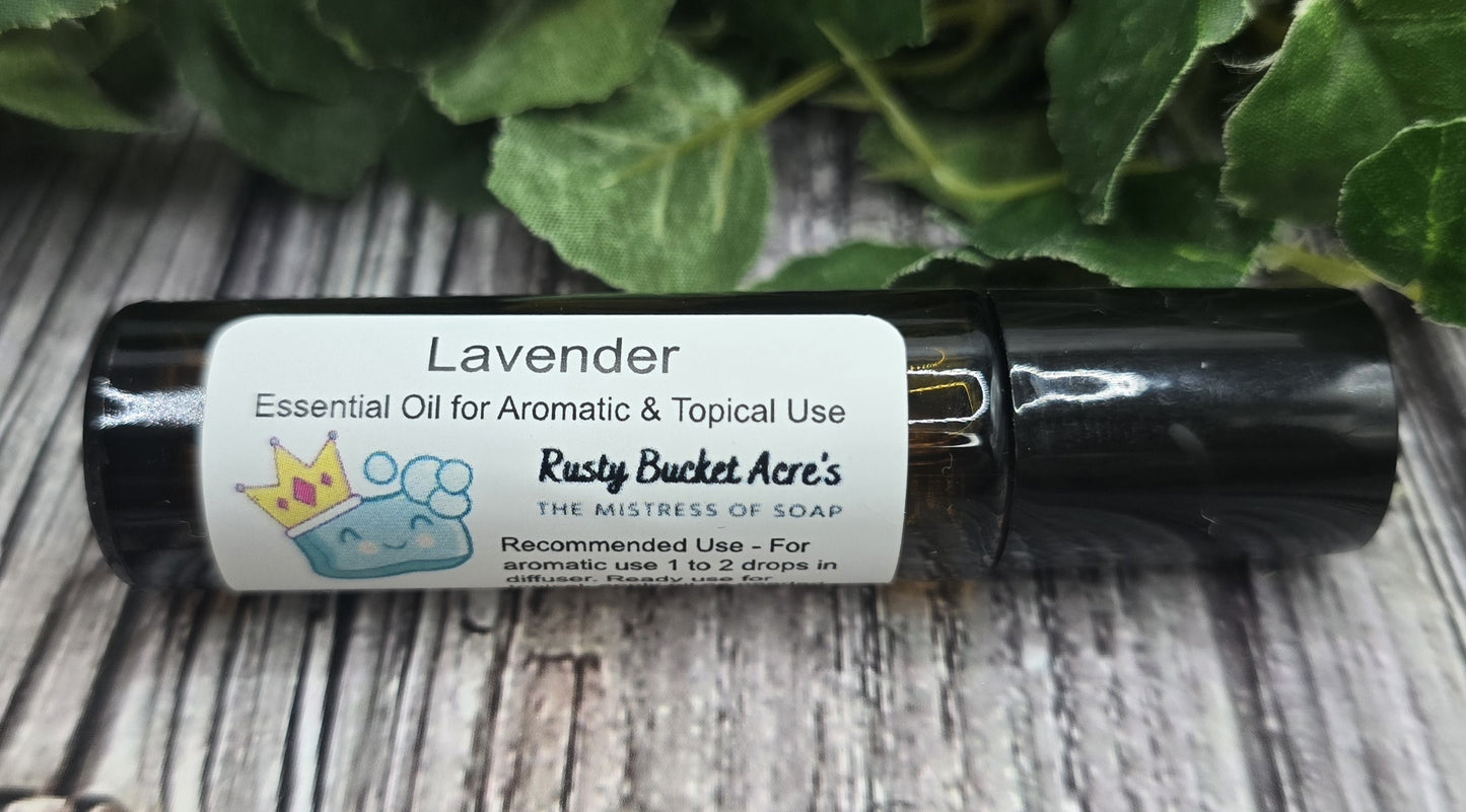 Roll-on bottle of lavender essential oil with a label on a wooden surface with green leaves in the background.