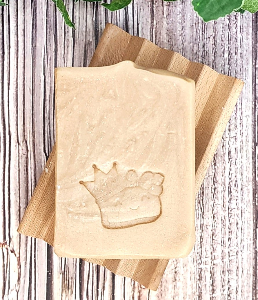 Whiteish Sassy Coconut Soap with a crown design on a wooden block against a wooden background