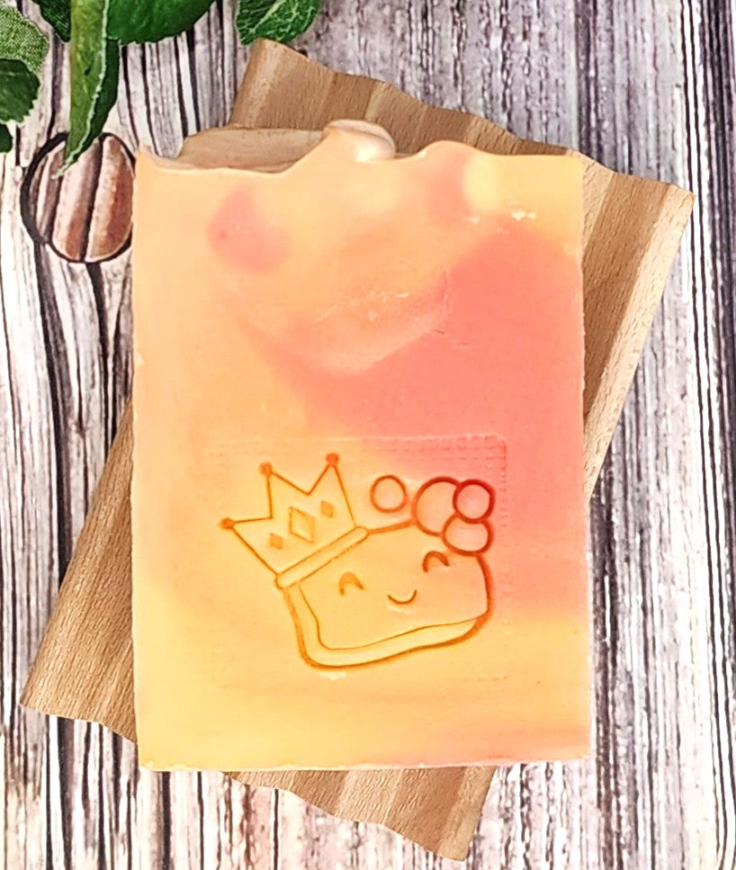 Tequila Sunrise Soap with a crown design on a wooden board against a wooden background
