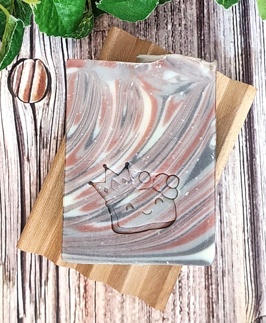 Marble-patterned soap with a crown design on a wooden coaster