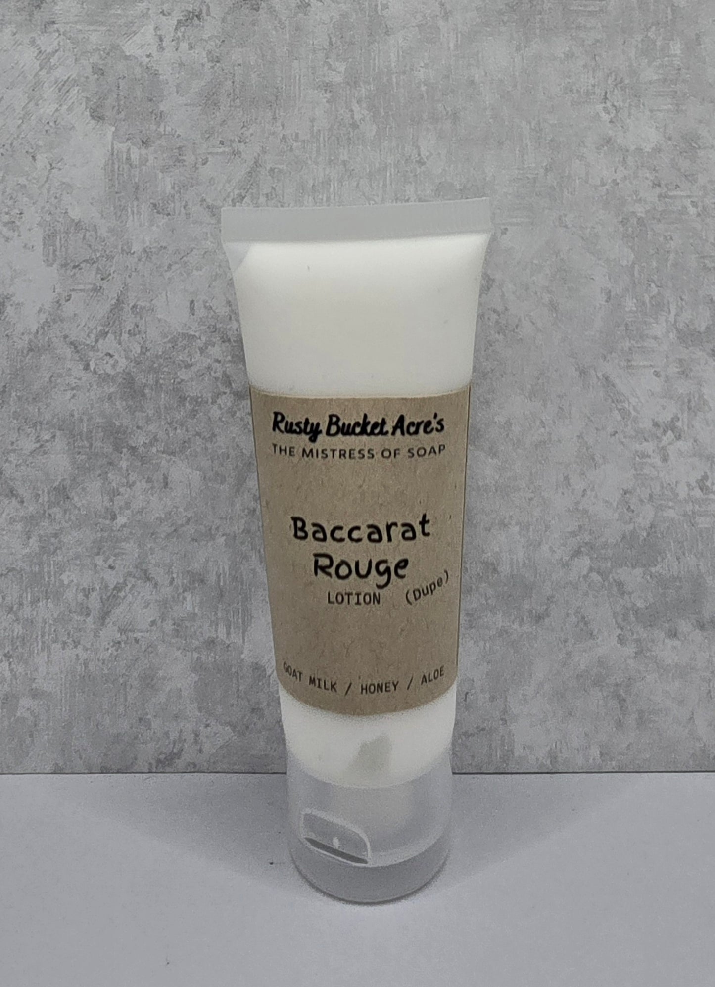 Tube of Baccarat Rouge Dupe lotion with a kraft paper label on a gray background