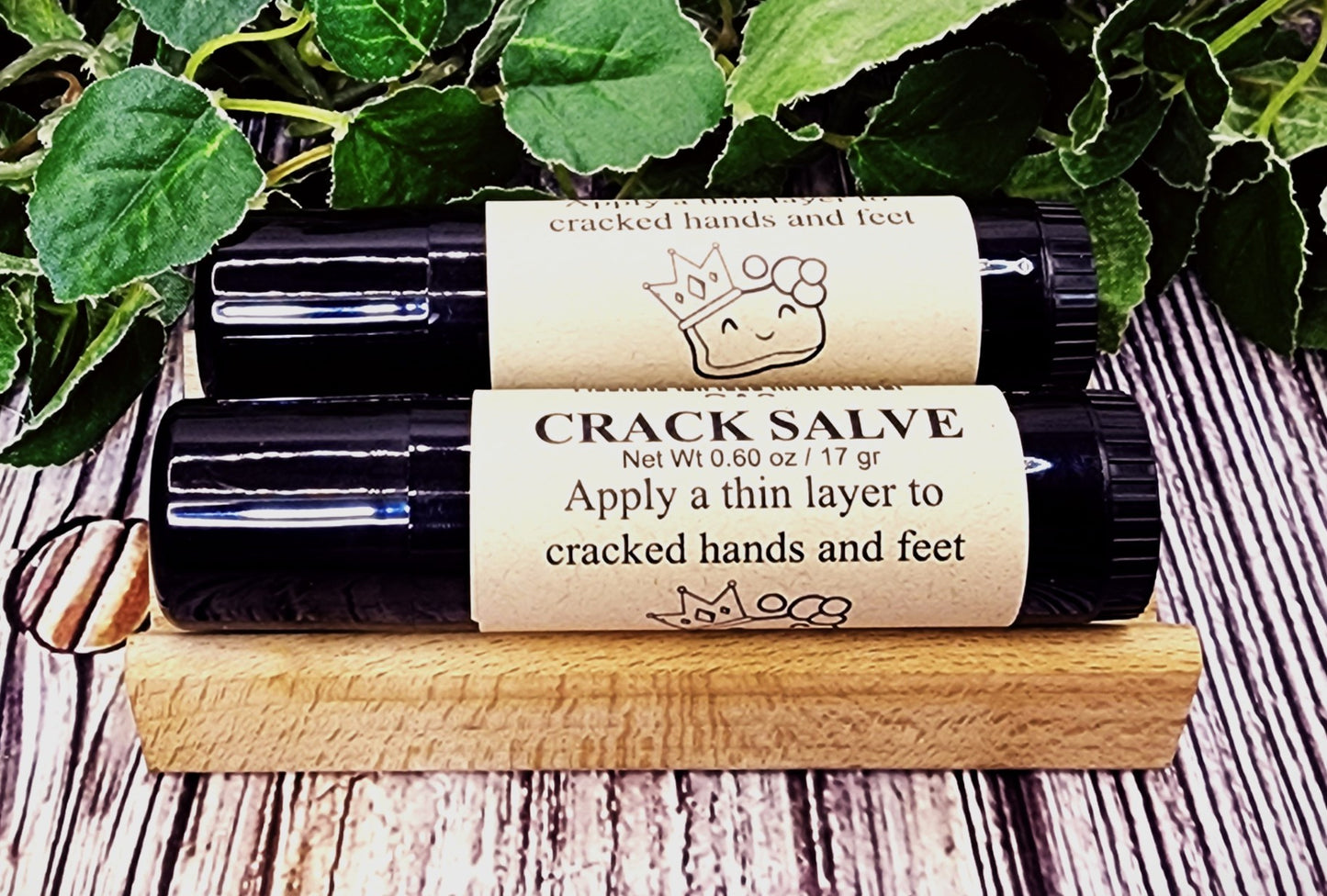 Two bottles of crack salve on a wooden block with green leaves in the background