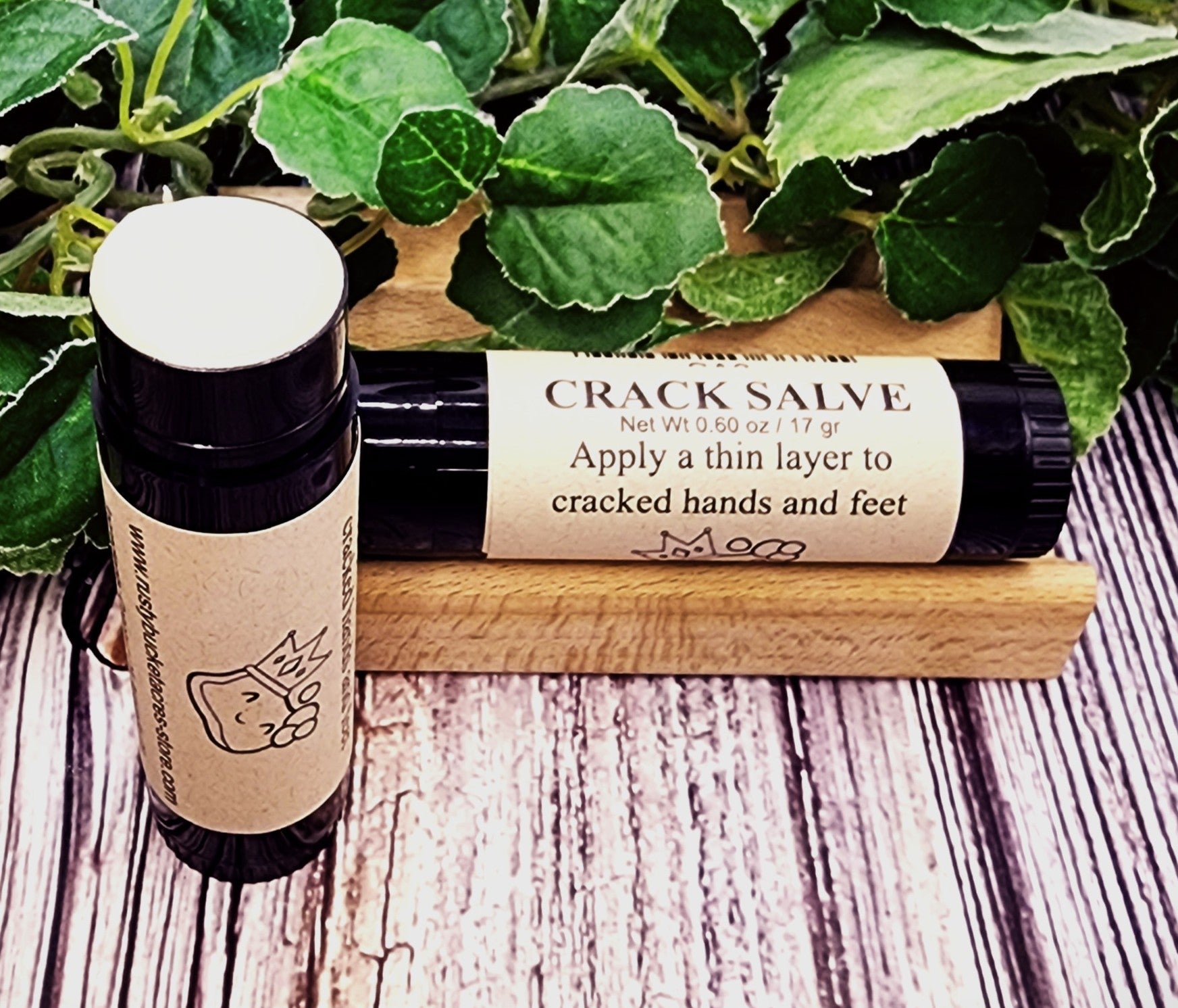 Crack salve with applicator on a wooden surface with green leaves in the background