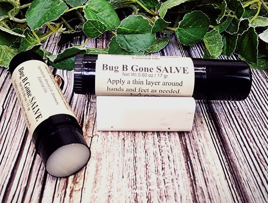 Bug B Gone Salve with packaging on a wooden surface with green leaves in the background