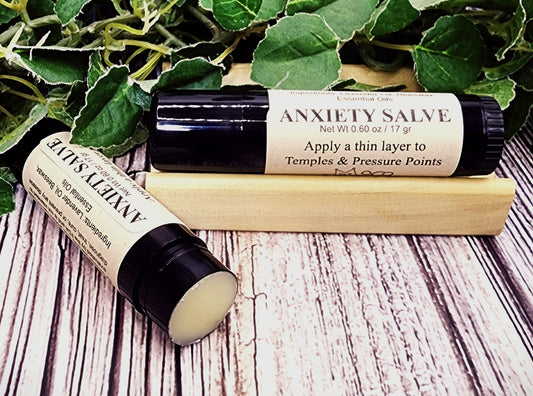 Two bottles of Anxiety Salve on a wooden surface with green leaves in the background