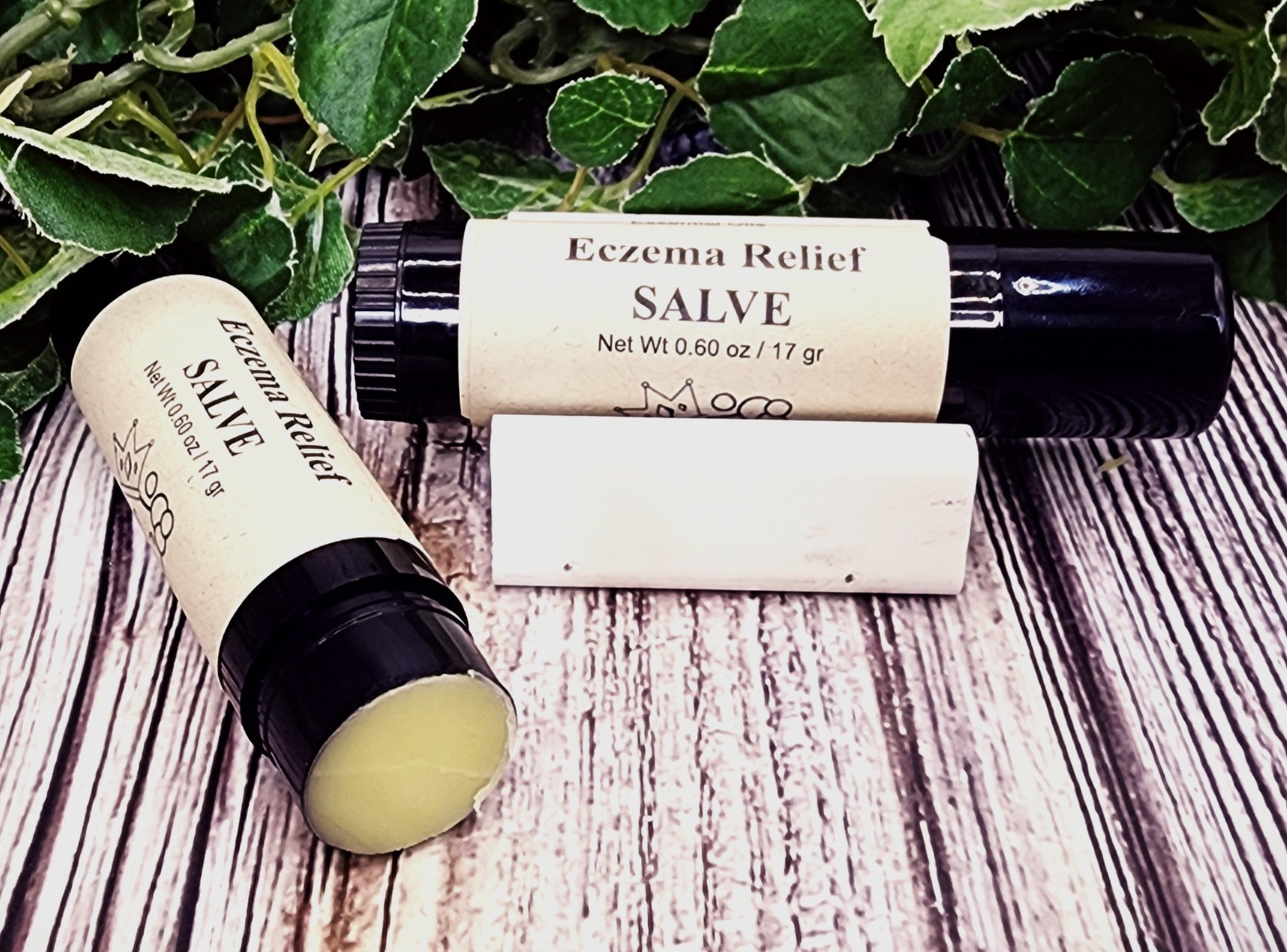 Eczema Relief Salve applicator on a wooden surface with green leaves in the background