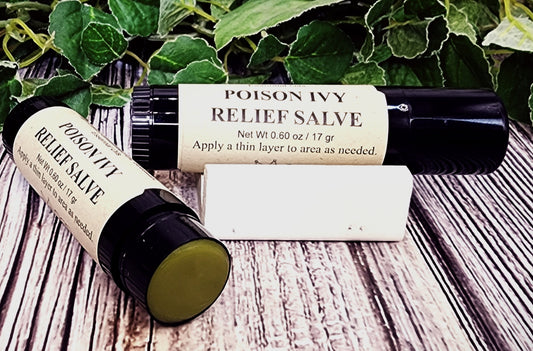 Two bottles of Poison Ivy Relief Salve on a wooden surface with green leaves in the background.