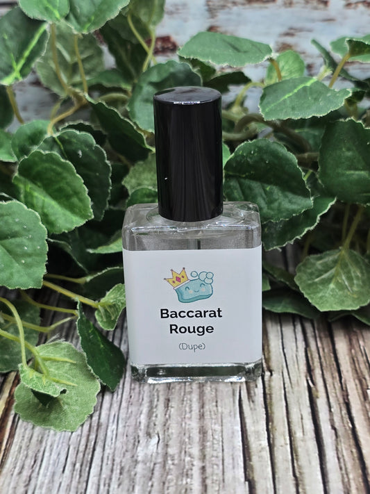 Baccarat Rouge perfume bottle on a wooden surface with green leaves in the background