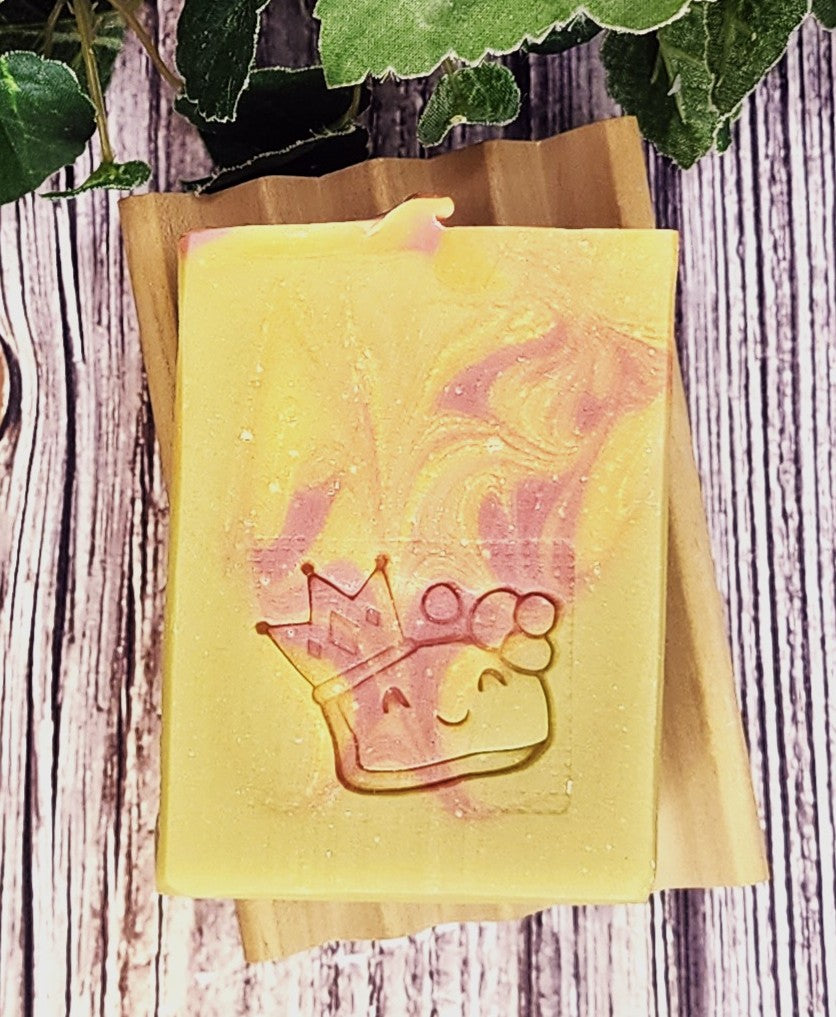 Yellow soap bar with a crown design on a wooden surface