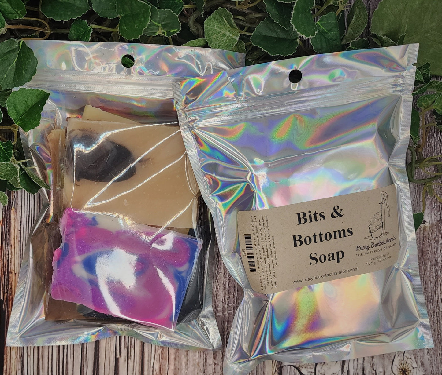 Iridescent packaging with soap bars and a label on a wooden surface with green leaves.