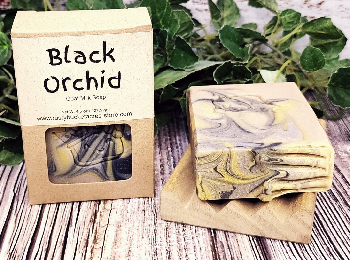 Black Orchid goat milk soap with packaging on a wooden surface