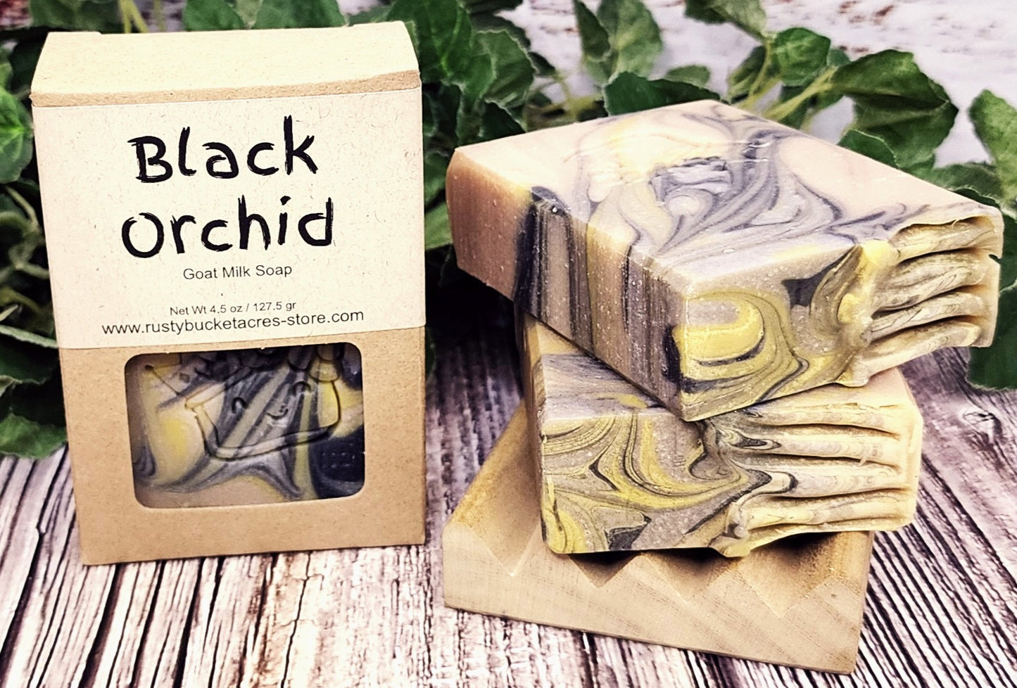 Black Orchid goat milk soap with packaging on a wooden surface