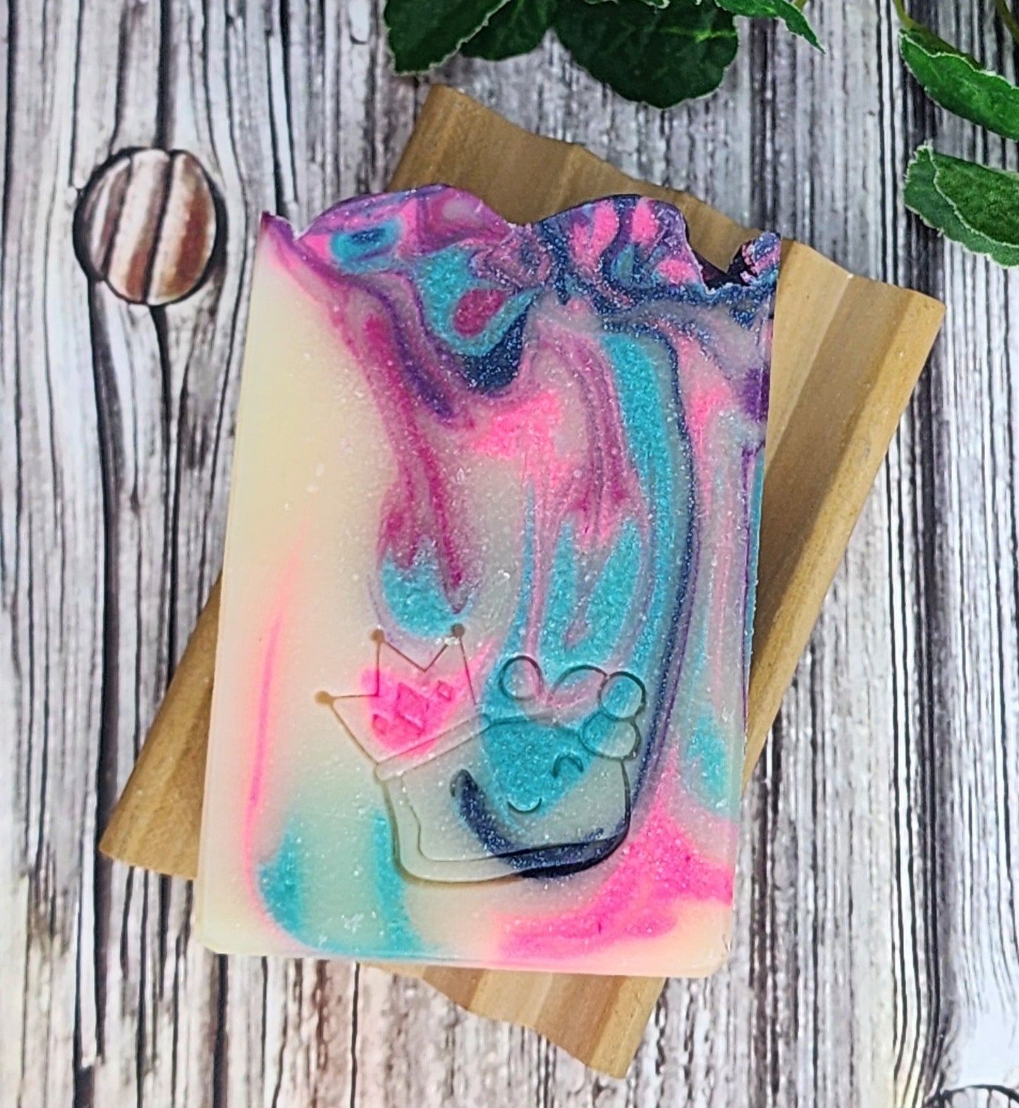 Colorful Blueberry Mint soap bar with a design on a wooden block against a rustic wooden background
