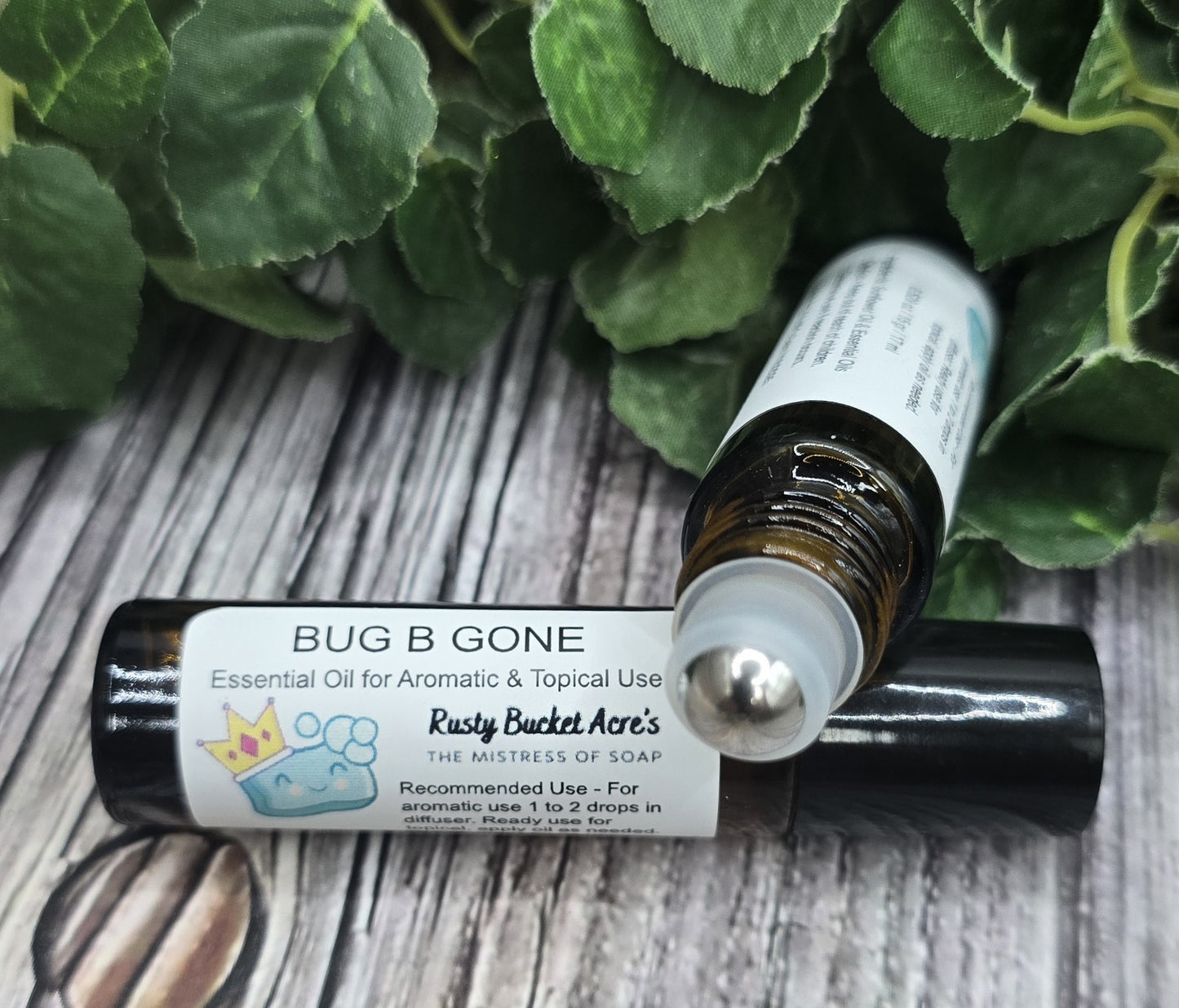 Roll-on bottle labeled 'Bug B Gone' on a wooden surface with green leaves in the background