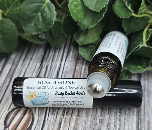 Roll-on bottle labeled 'Bug B Gone' on a wooden surface with green leaves in the background