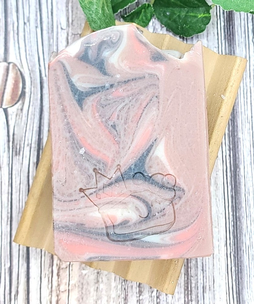 Cherry Elixir soap bar with marble design on a wooden soap dish with leaves.