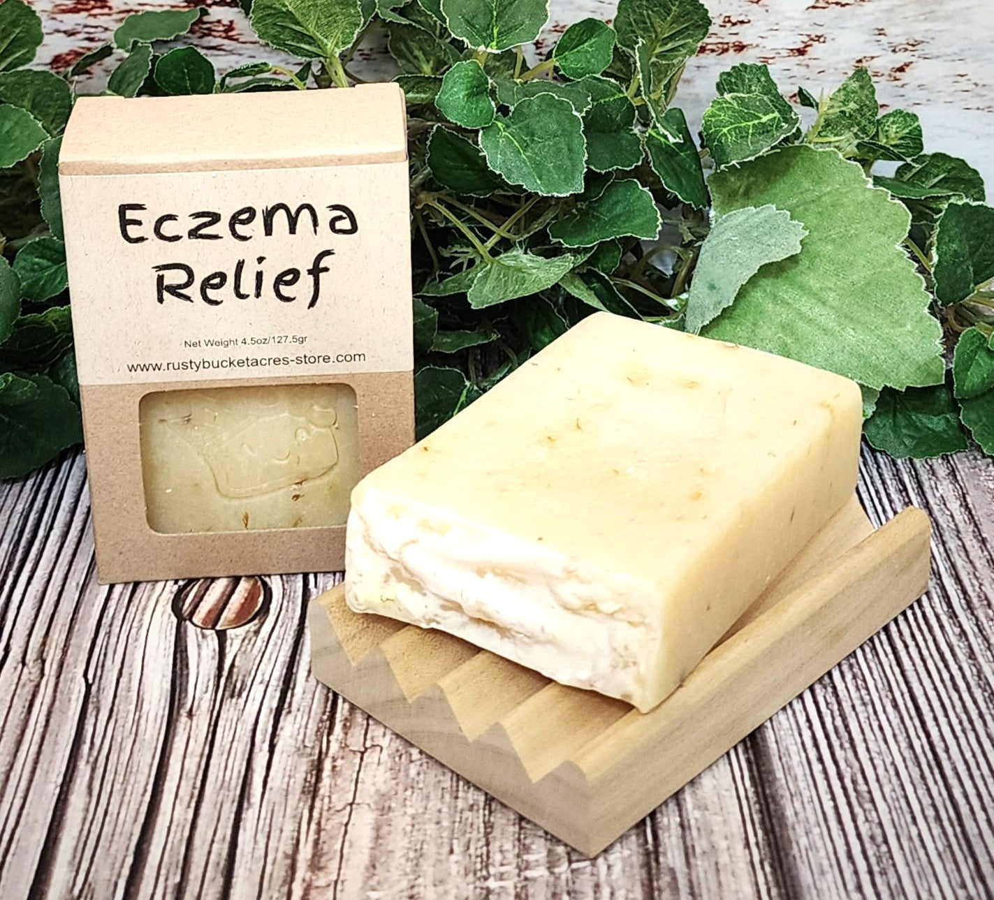 Bar of soap with 'Eczema Relief' packaging on a wooden surface with green leaves in the background