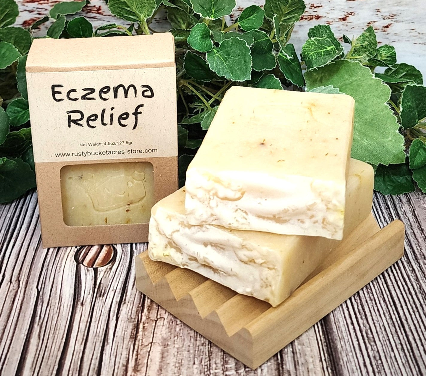 Bar of soap with 'Eczema Relief' packaging on a wooden stand with greenery in the background.