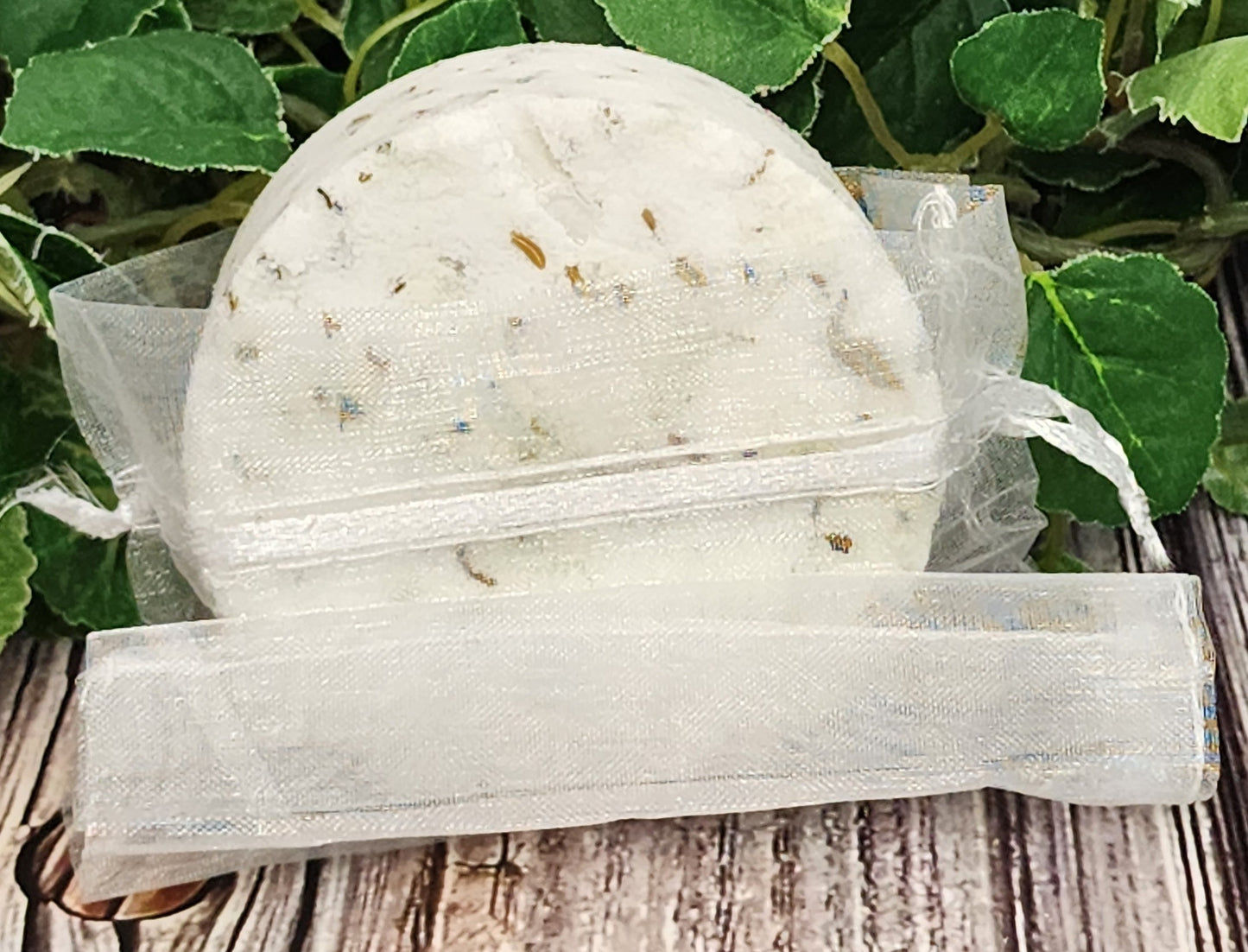 Bath bomb in a clear plastic bag with green leaves in the background