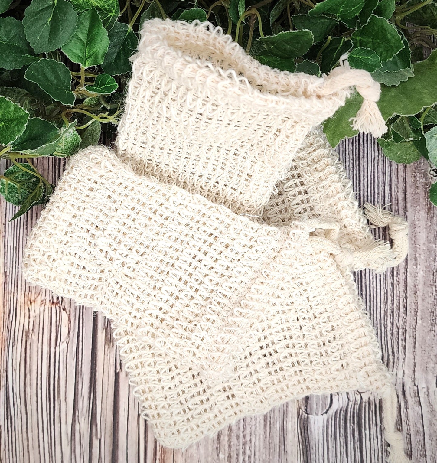 natural fiber soap bags on a wooden surface with green leaves in the background