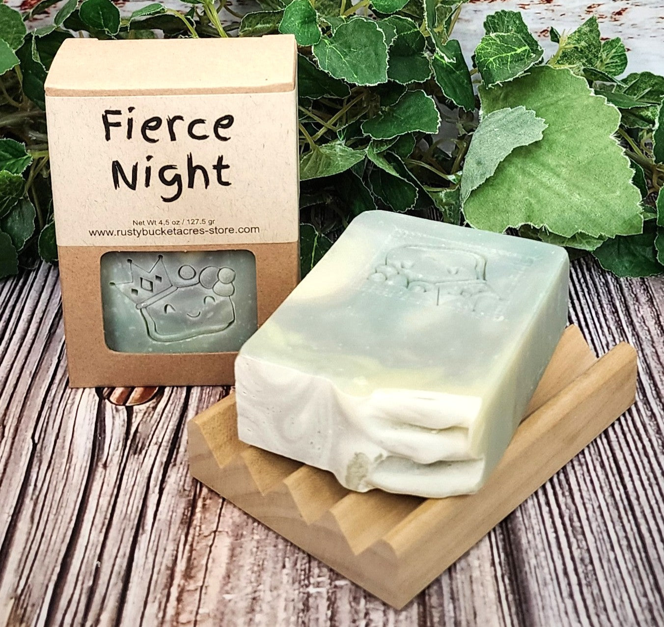 Bar of soap on a wooden stand with 'Fierce Night' packaging and green leaves in the background