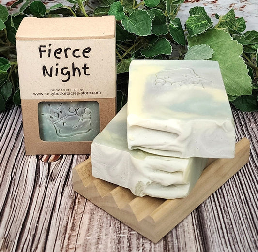 Two bars of soap on a wooden stand with a 'Fierce Night' packaging in the background.