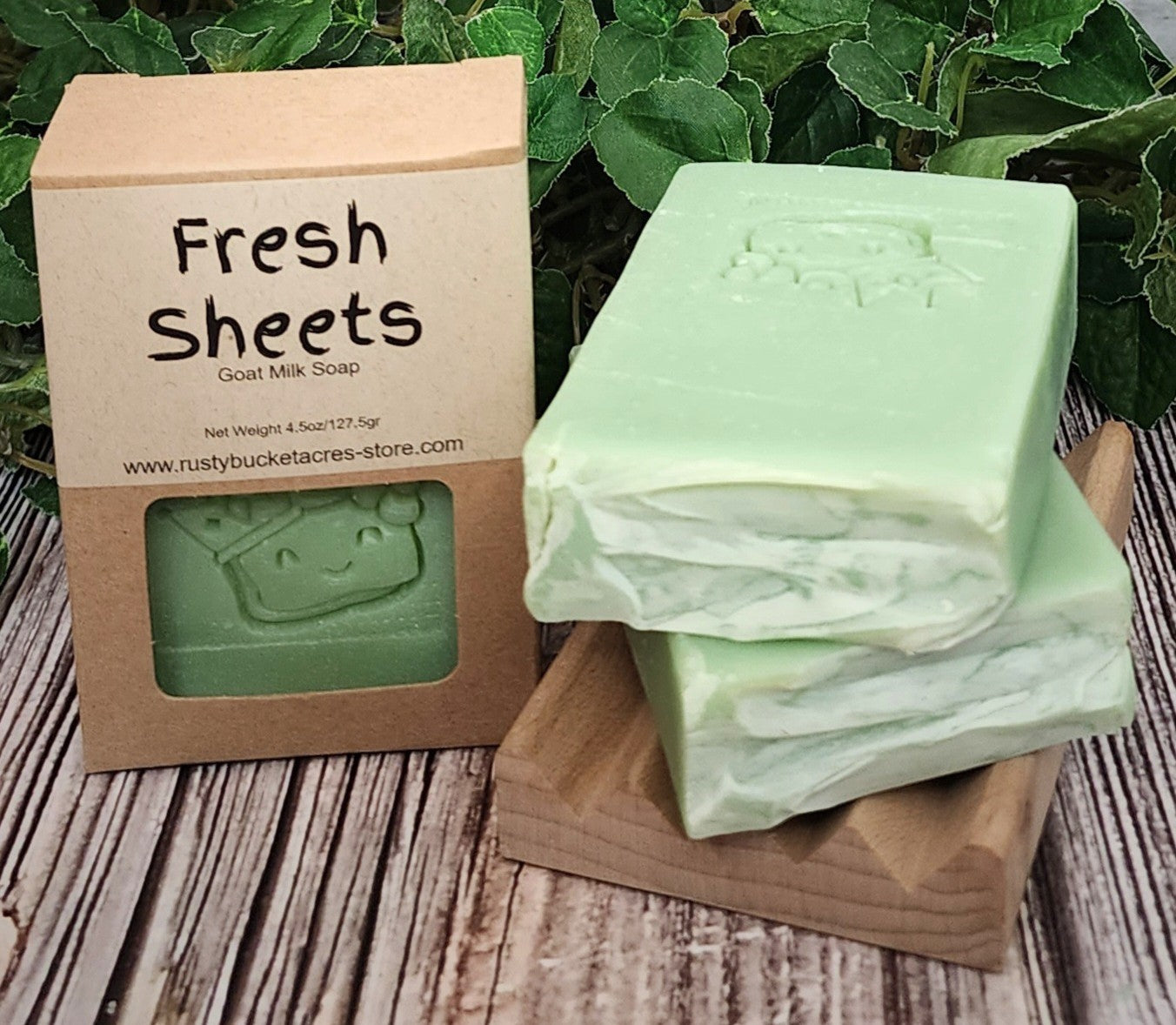 Green goat milk soap with a 'Fresh Sheets' label on a wooden block and packaging.