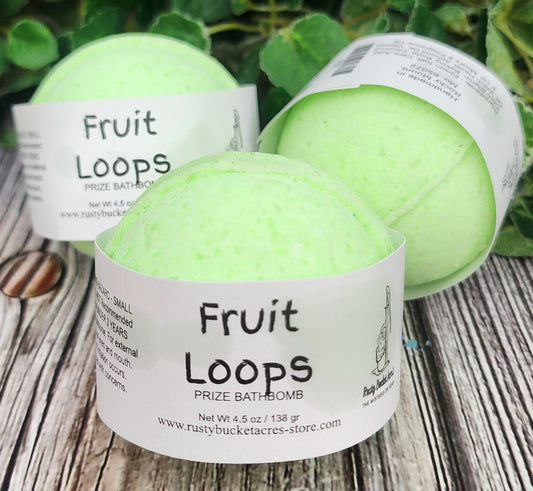 Three green bath bombs labeled 'Fruit Loops' on a wooden surface with leaves in the background.