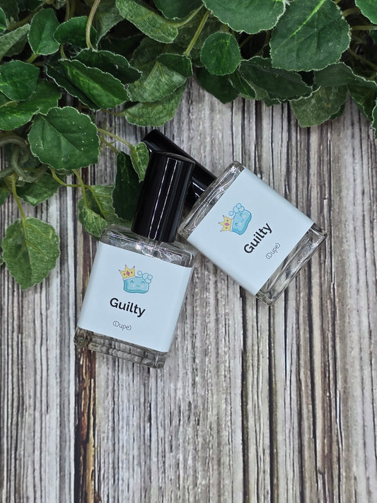 Two small bottles labeled 'Guilty' on a wooden surface with green leaves.