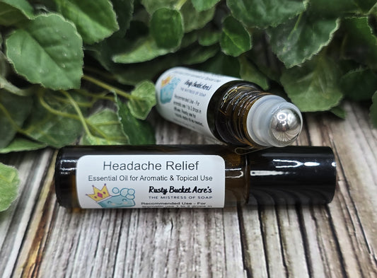 Two essential oil bottles labeled 'Headache Relief' on a wooden surface with green leaves in the background.