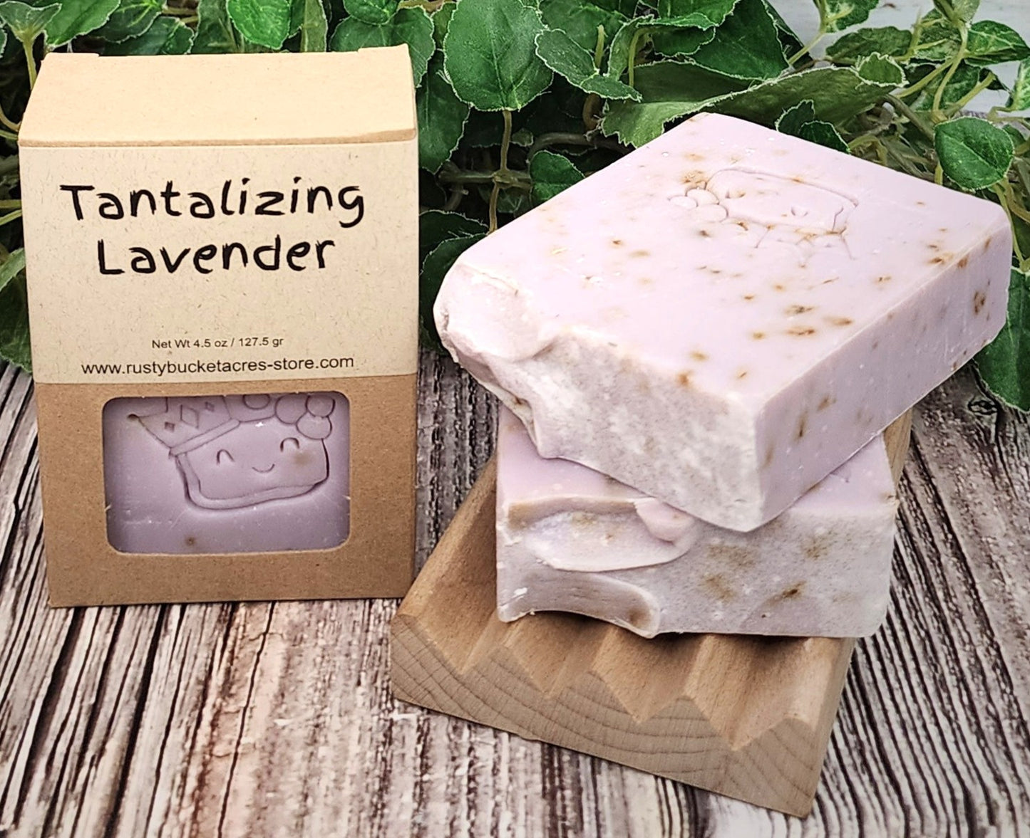 Tantalizing Lavender soap with packaging on a wooden surface with greenery in the background