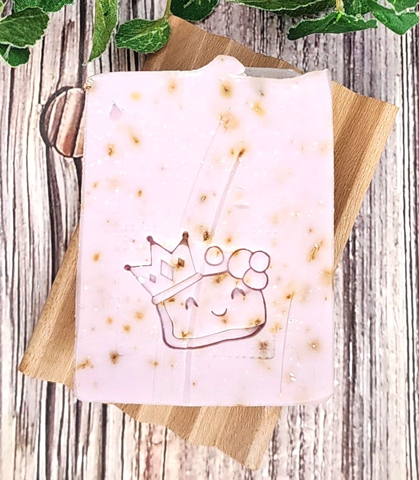 Pinkish soap with a crown design on a wooden surface