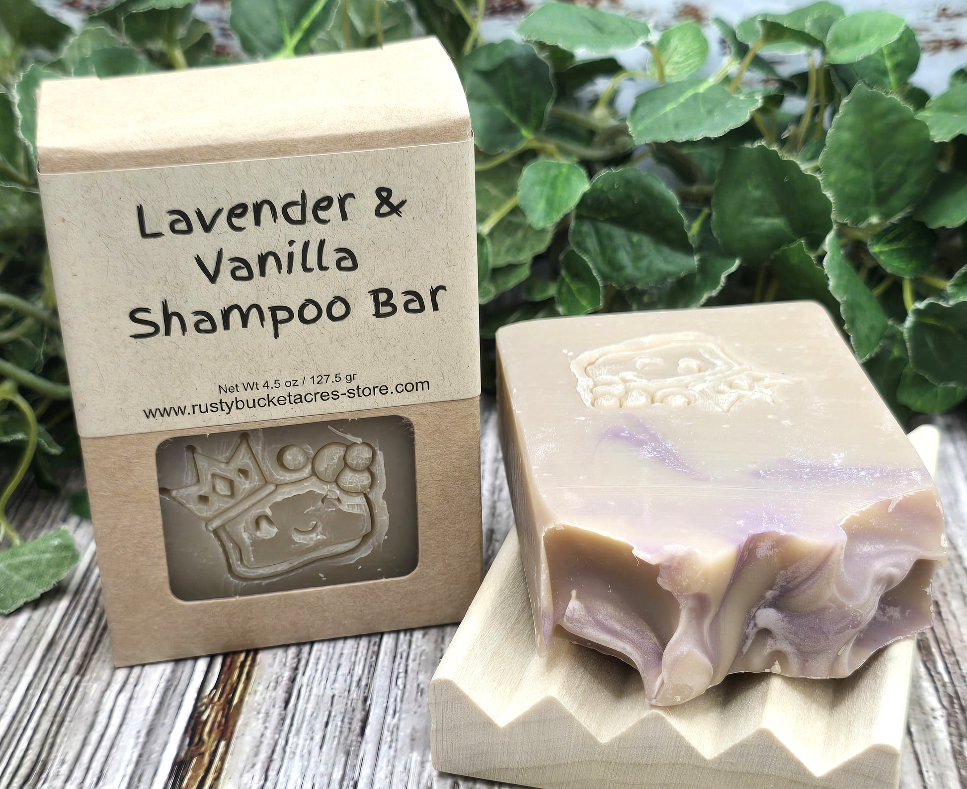 Lavender & Vanilla Shampoo Bar with packaging on a wooden surface with greenery in the background