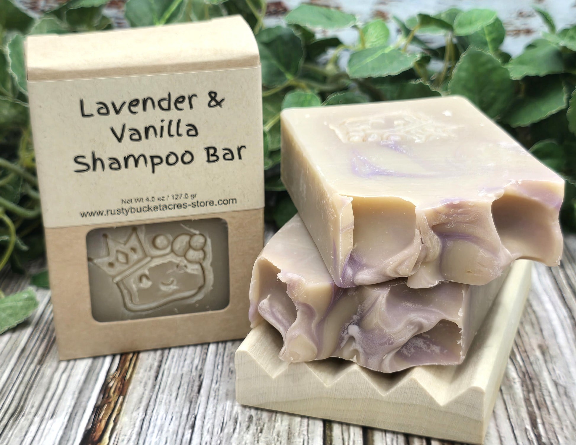 Lavender & Vanilla shampoo bar with packaging on a wooden surface with greenery in the background