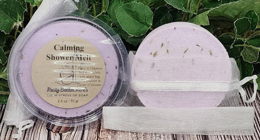 Two purple bath products with labels on a wooden surface with green leaves in the background