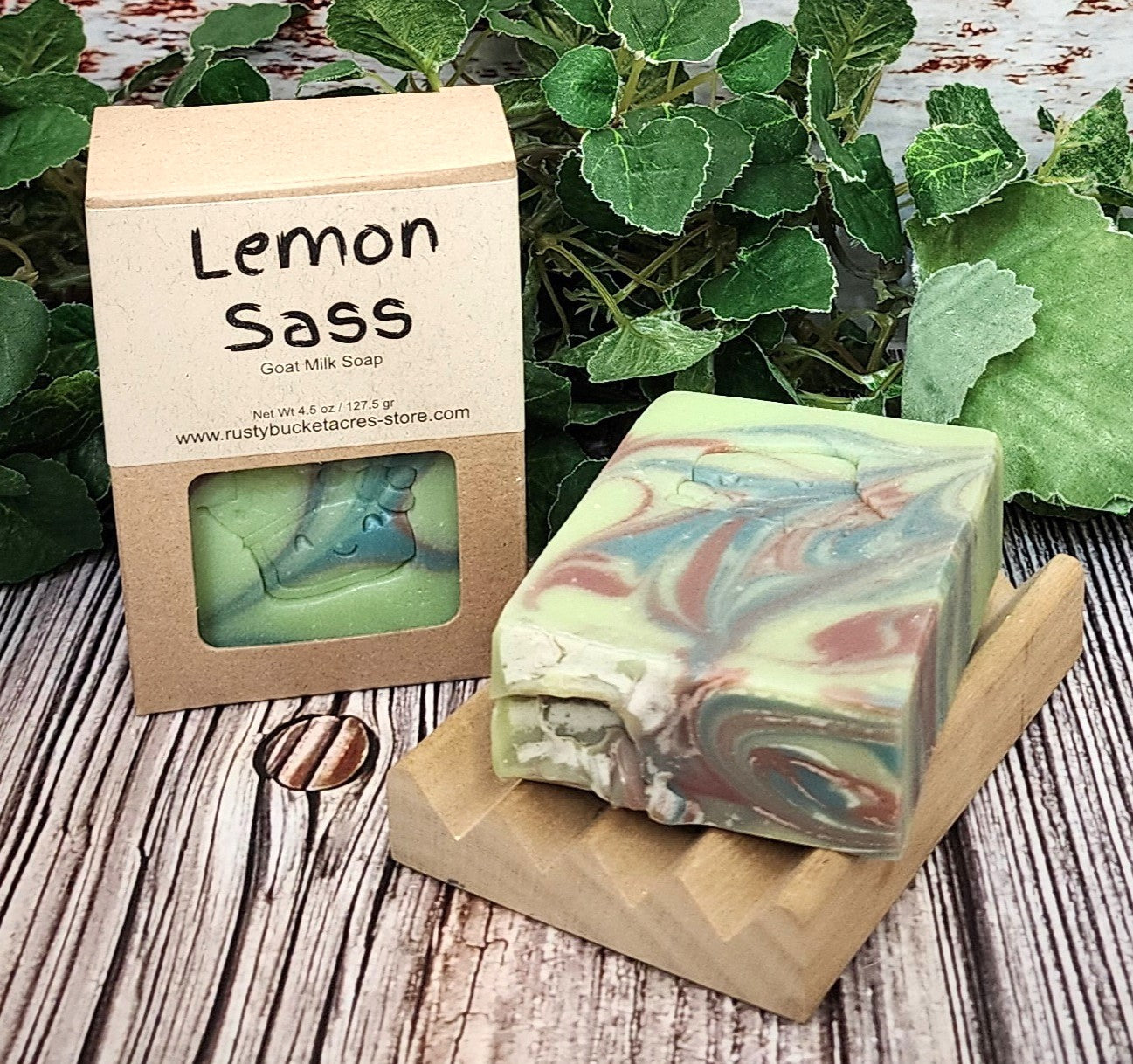 Marbled soap bar with 'Lemon Sass' packaging on a wooden surface with greenery.