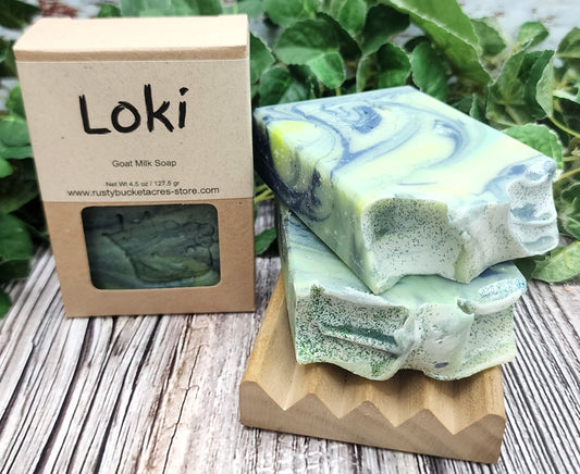 Two bars of green and blue swirled soap on a wooden stand with a 'Loki' soap box in the background.