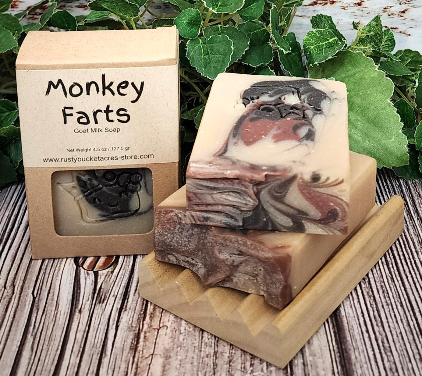 Goat milk soap with 'Monkey Farts' packaging on a wooden surface with green leaves in the background