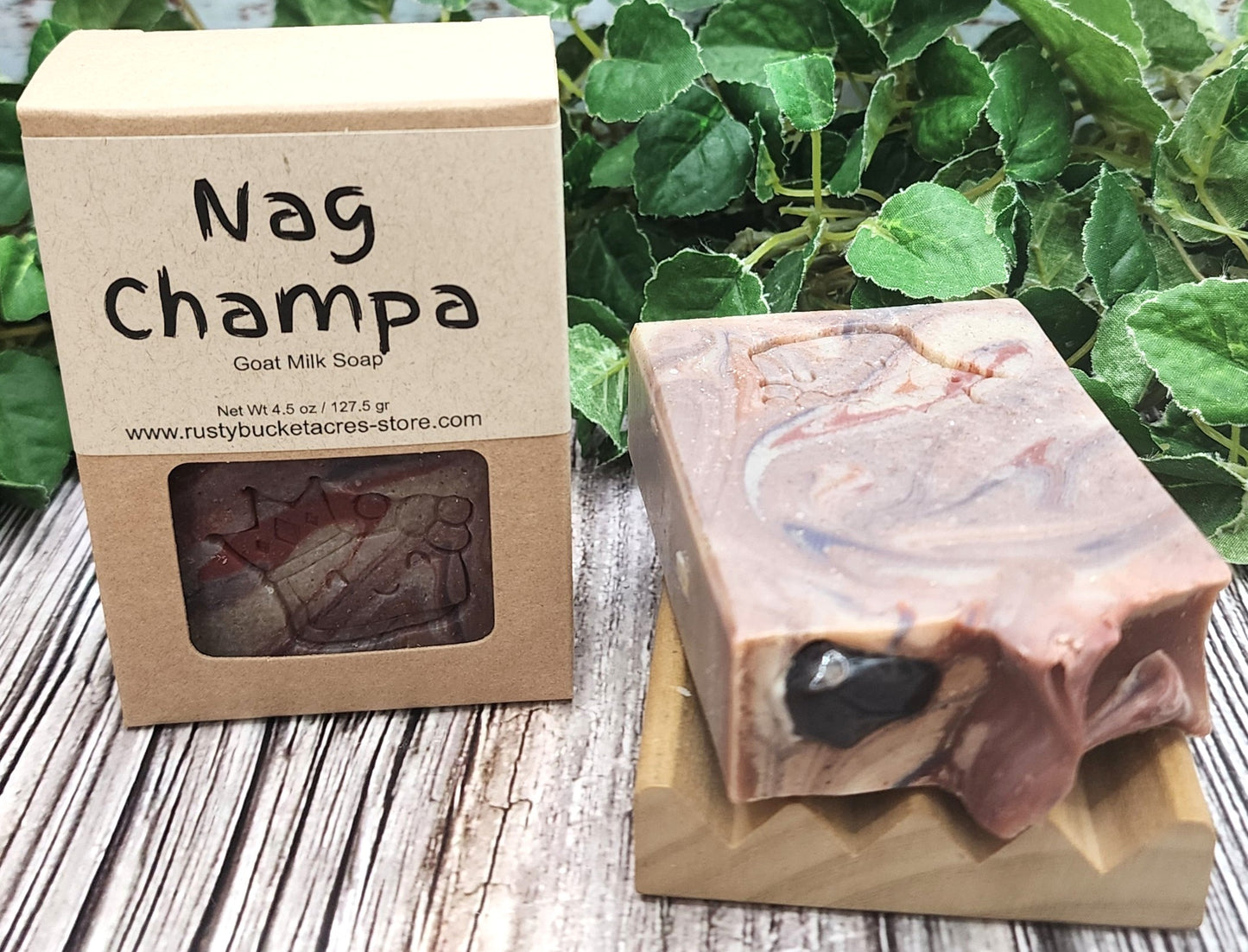 Goat milk soap with a visible brand name on a wooden surface with greenery in the background