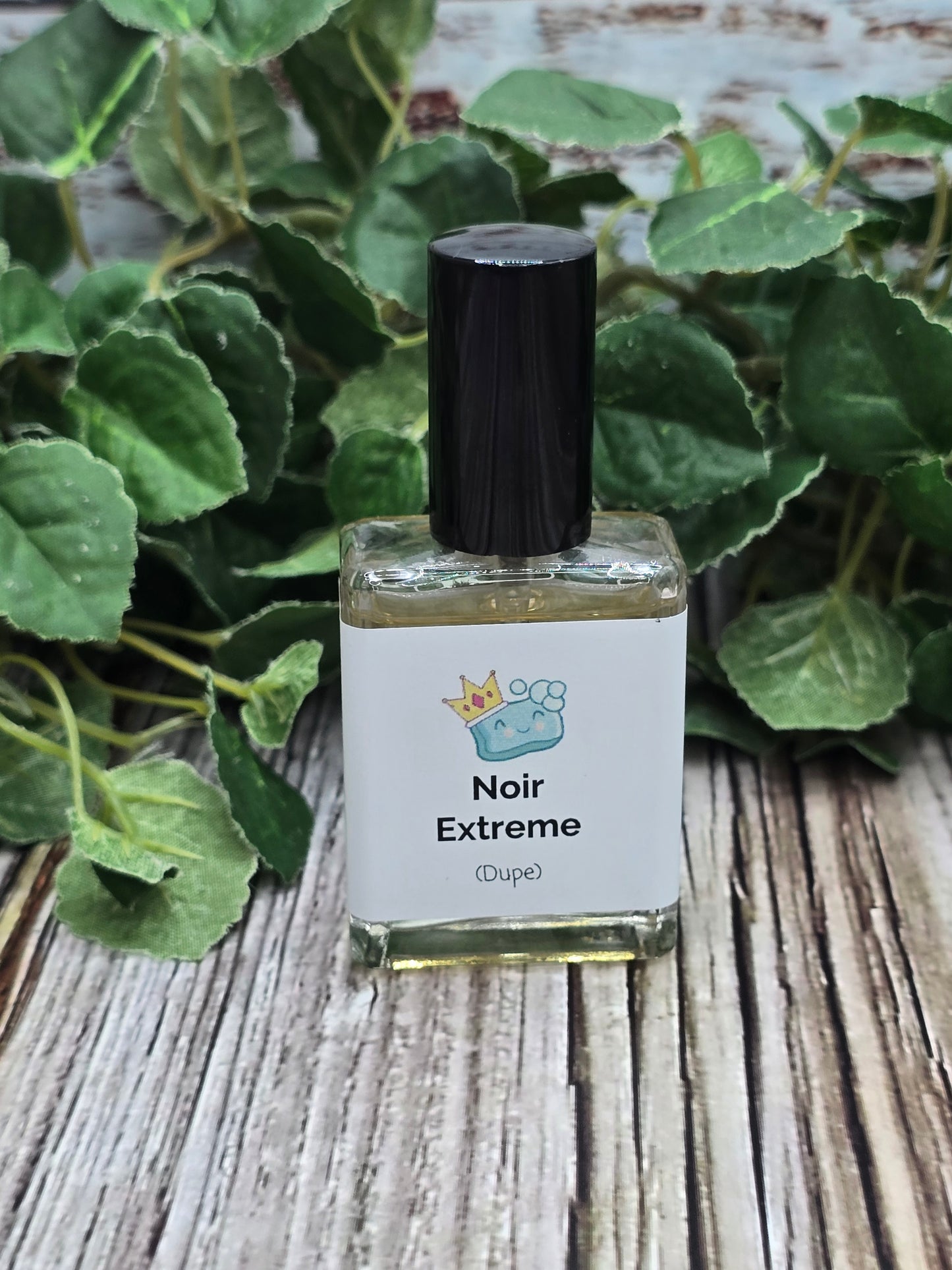 Perfume bottle labeled 'Noir Extreme' on a wooden surface with green leaves in the background