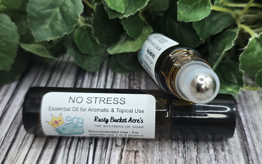 Two essential oil bottles labeled 'NO STRESS' on a wooden surface with green leaves in the background.
