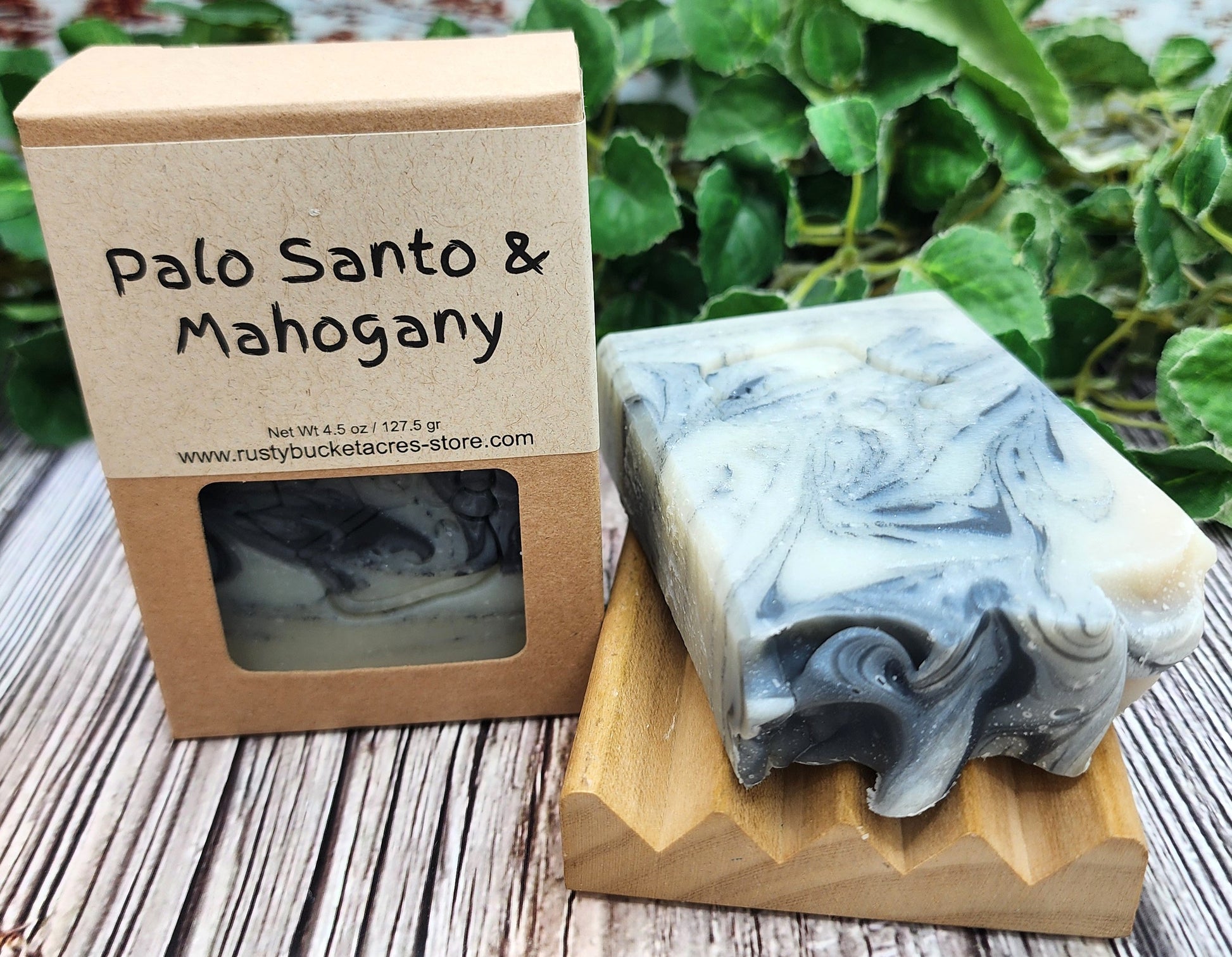 Bar of soap with marbled design next to a box labeled 'Palo Santo & Mahogany' on a wooden surface.