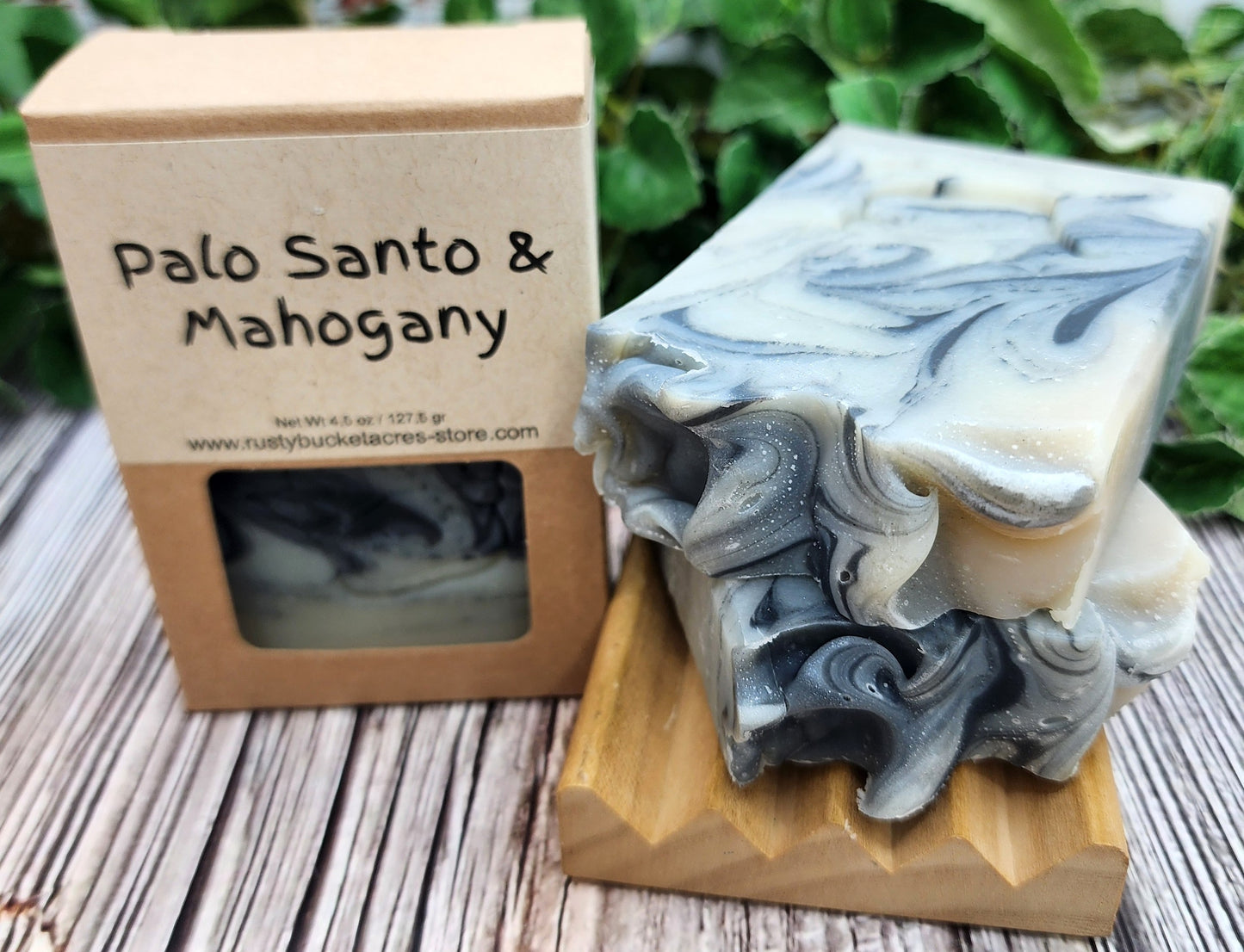 Marbled soap bar on a wooden stand with a 'Palo Santo & Mahogany' packaging in the background.