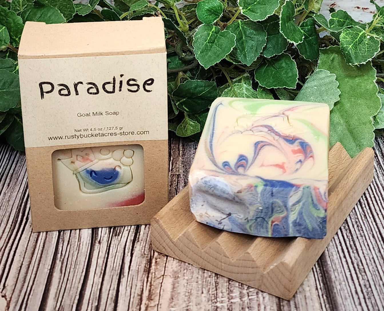 Colorful soap bar with 'Paradise' packaging on a wooden surface with greenery in the background