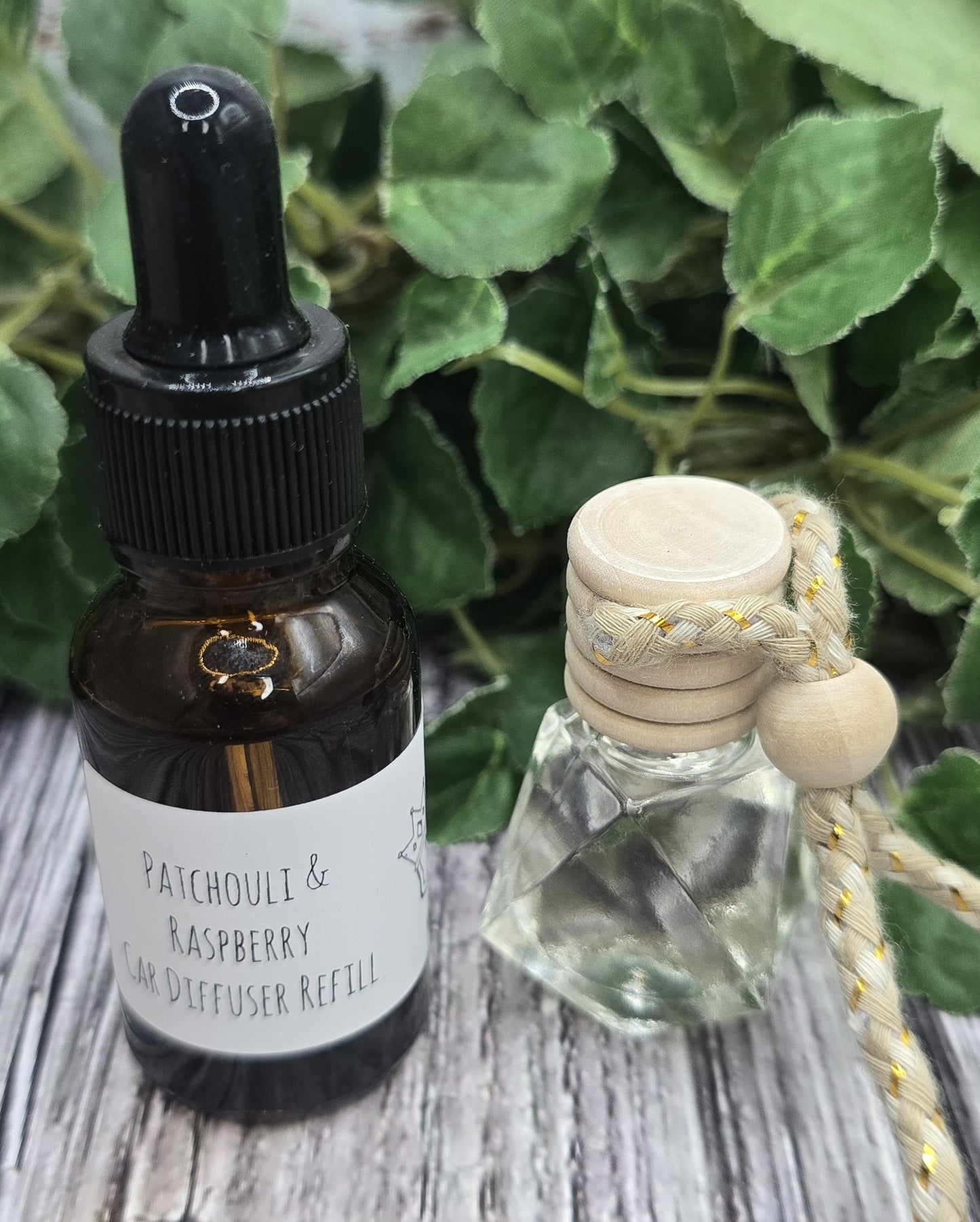 Two bottles on a wooden surface with green leaves in the background