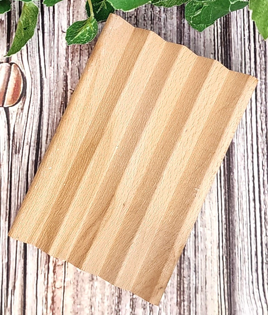 Wooden soap dish with groves on a rustic wooden surface with green leaves.