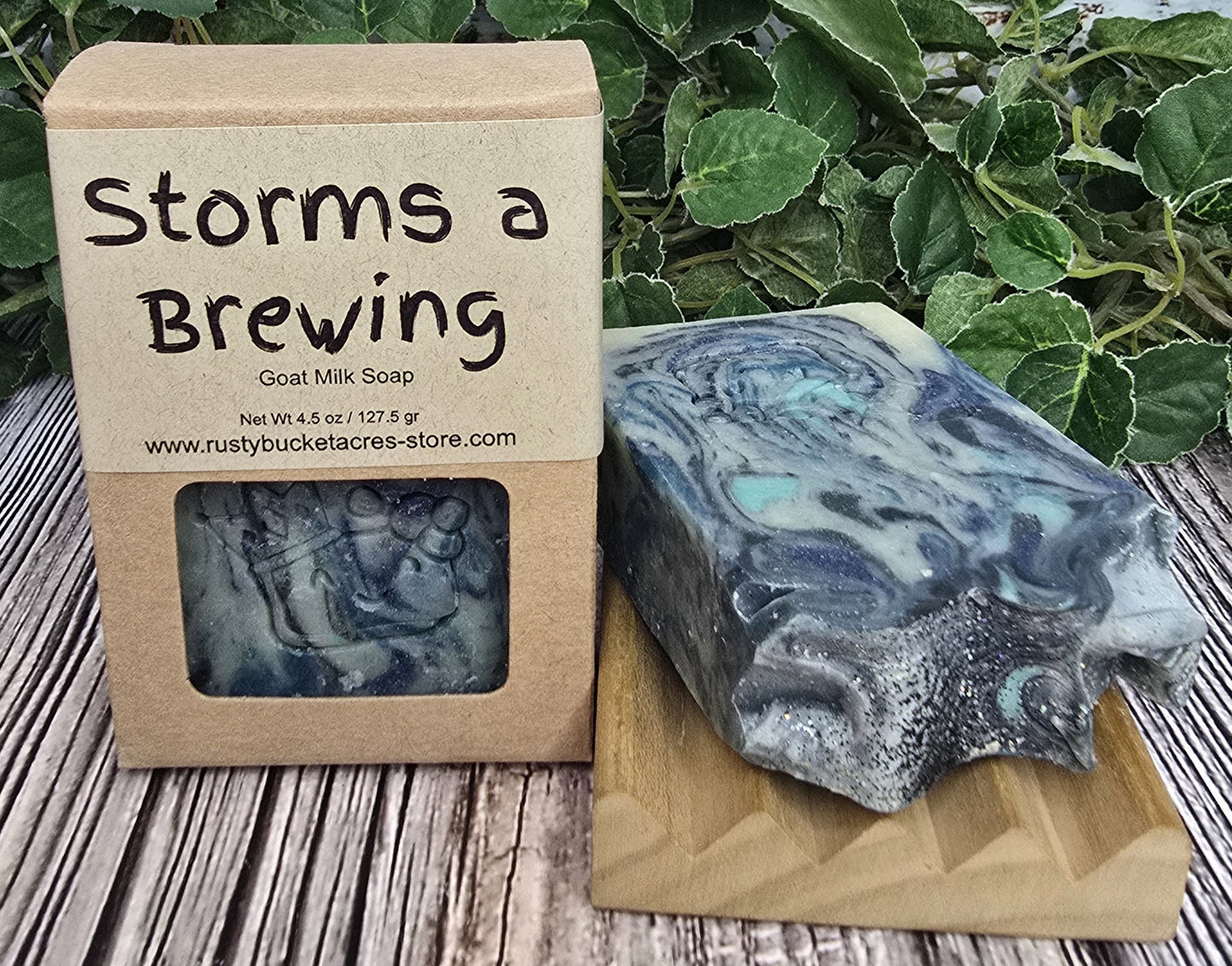 Bar of soap with 'Storms a Brewing' packaging on a wooden surface with greenery in the background